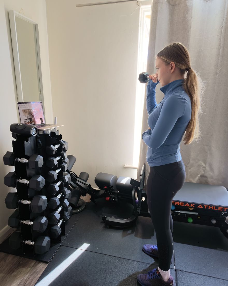 Liubov doing a dumbbell curl in front of her laptop
