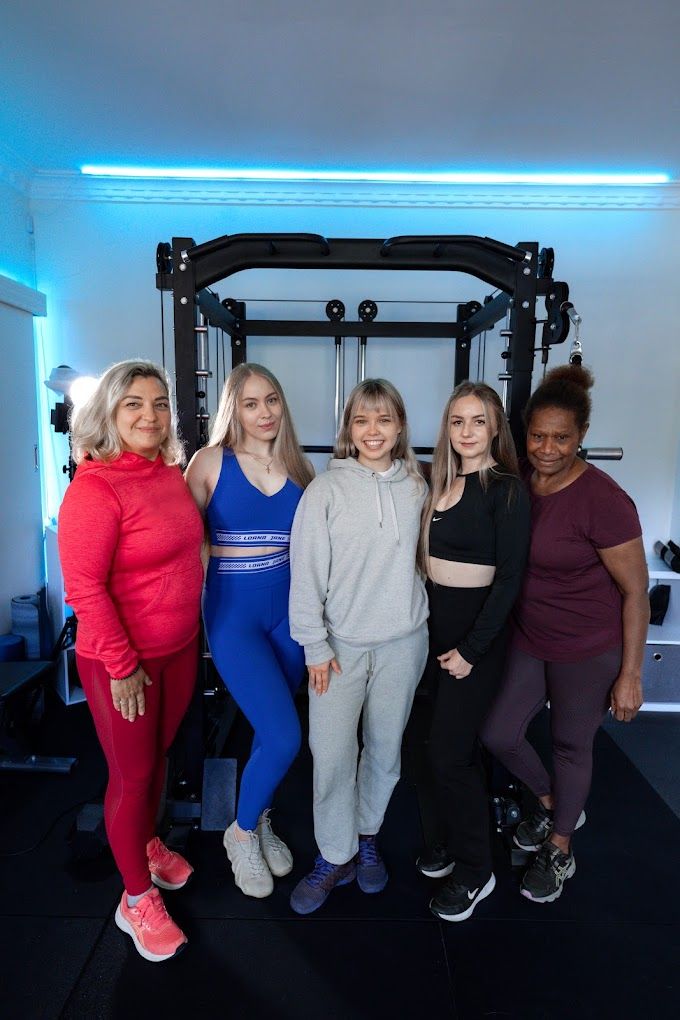 Liubov with four of the women she coaches, standing in front of a squat rack