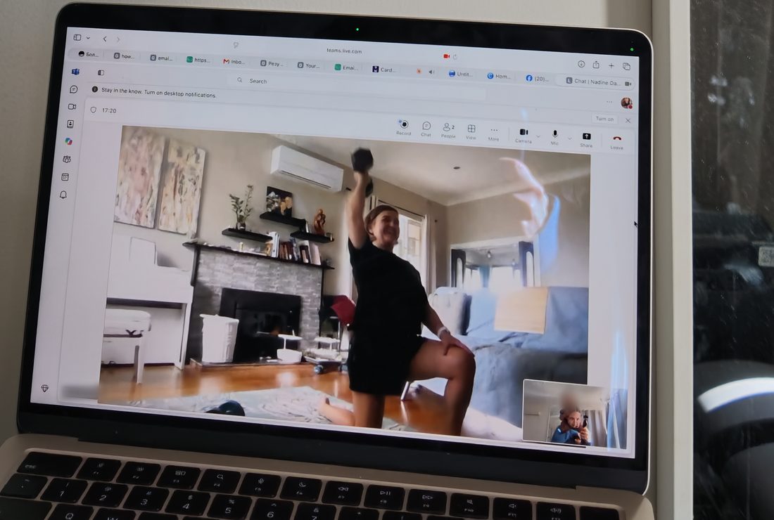 A client doing a lunge with a dumbbell, seen on Liubov's laptop during a video call
